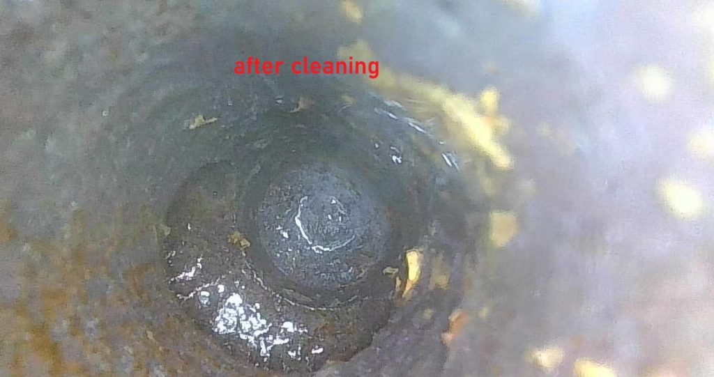 Thick layer of extracted iron rust sludge and clear bare metal cooling channel after flushing